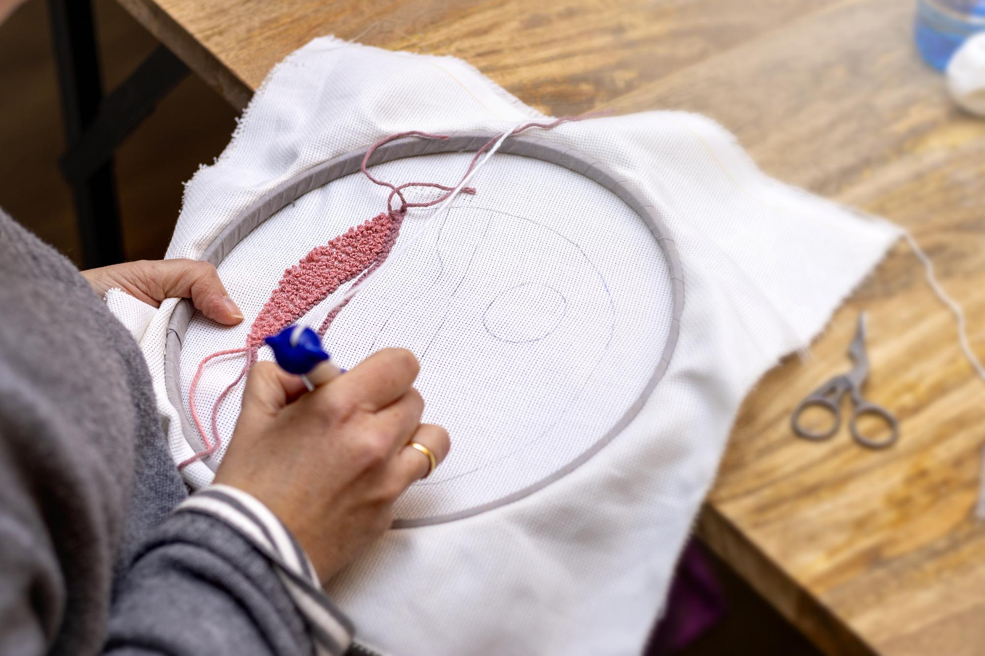 Hands embroidering detail in studio
